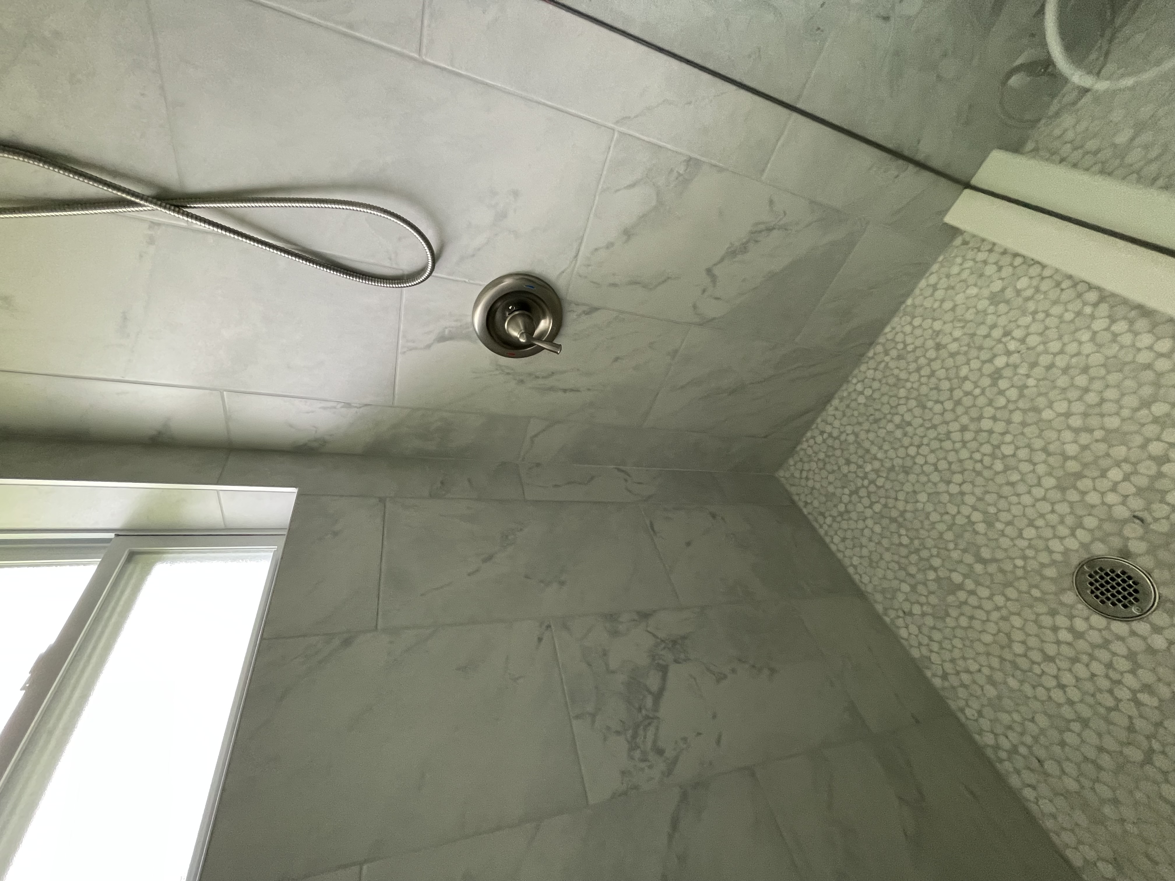 Large-format gray marble-look porcelain shower surround with pebble floor, Pinellas County FL